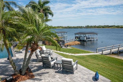 backyard turf pavers palm trees and outdoor furniture with waterfront view